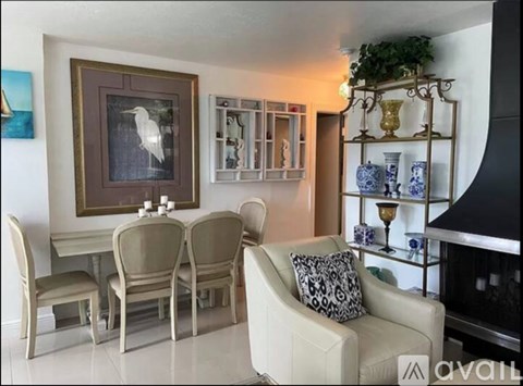 A living room with a white couch, chairs, and a painting on the wall.