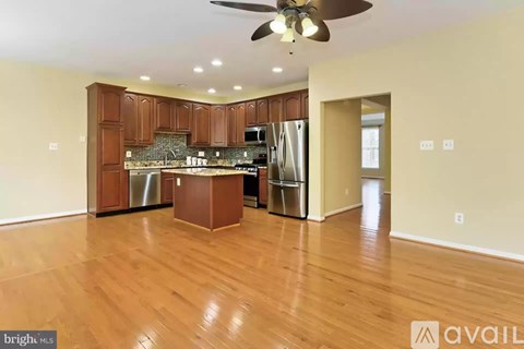 A kitchen with wooden cabinets and a fan on the ceiling.