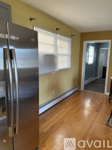 A kitchen with a stainless steel refrigerator and wooden floors.