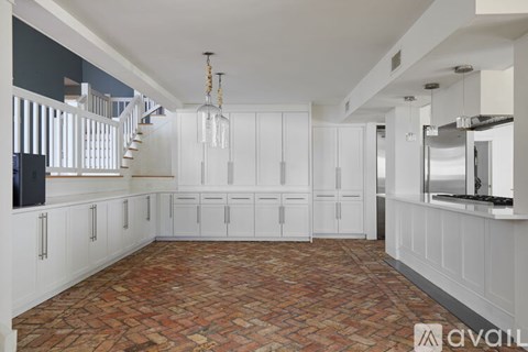A kitchen with white cabinets and a red tile floor.