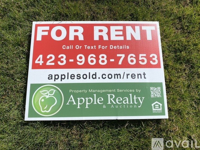 A red and white For Rent sign from Apple Realty.