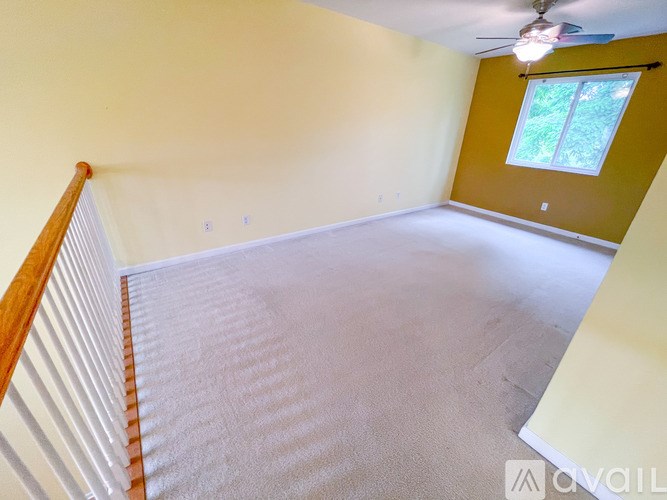 A room with a carpeted floor and a window with a view of trees.