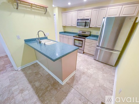 A kitchen with a blue countertop and a stainless steel refrigerator.