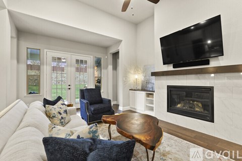 A living room with a fireplace and a television mounted above it.