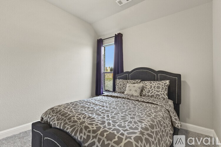 A bedroom with a large bed and a window with curtains.