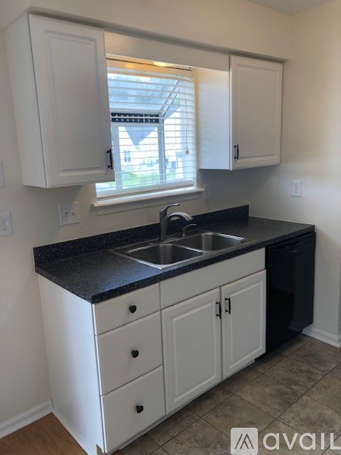 A kitchen with white cabinets and a black countertop.