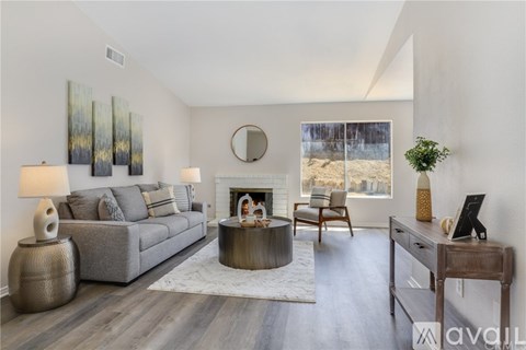 A modern living room with a grey sofa, a fireplace, and a painting on the wall.
