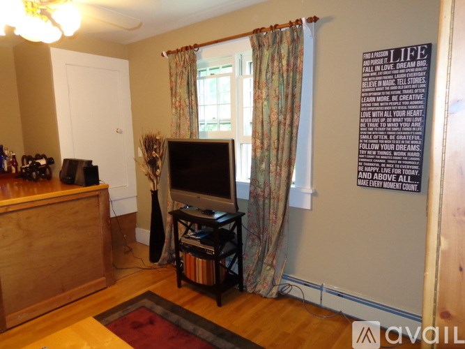 A living room with a television, a cabinet, and a vase on a table.