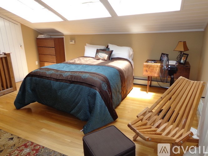 A bedroom with a bed, a chair, and a nightstand.