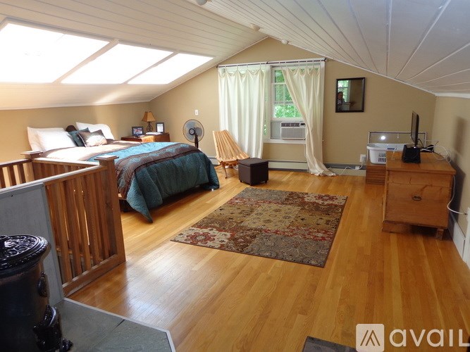 A bedroom with a bed, a chair, and a fan.