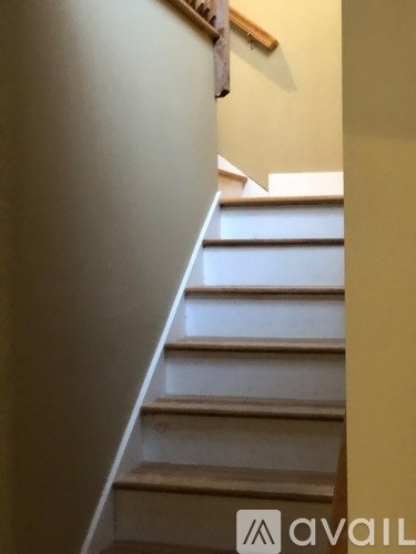 A staircase with a wooden handrail and white steps.
