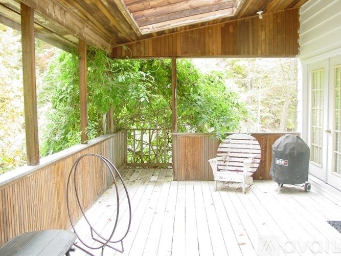 A wooden deck with a black chair and a white chair.