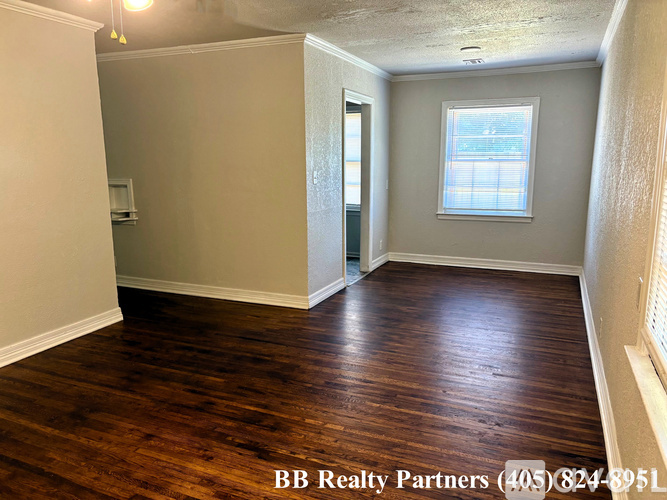 A room with wooden floors and a window with BB Realty Partners written on the bottom.