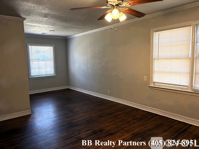 A room with a ceiling fan and wooden floors.