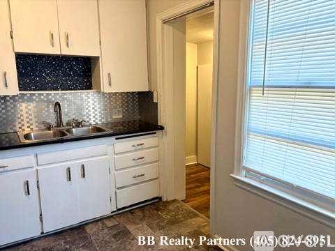 A kitchen with white cabinets and a black countertop with a sink.