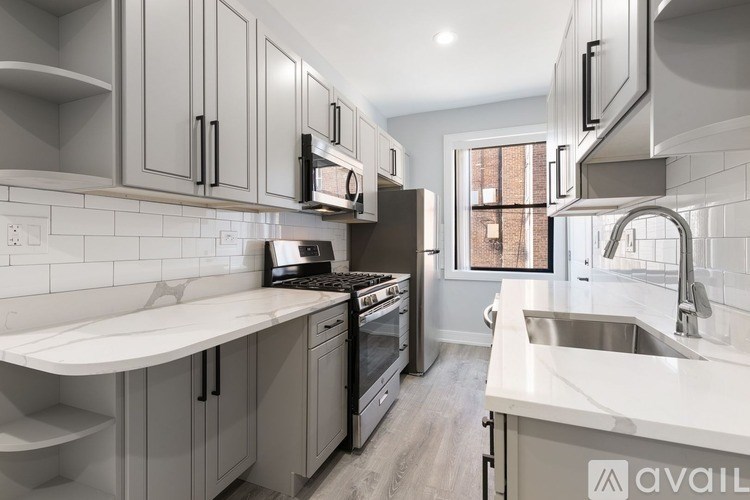 A modern kitchen with a white countertop and stainless steel appliances.