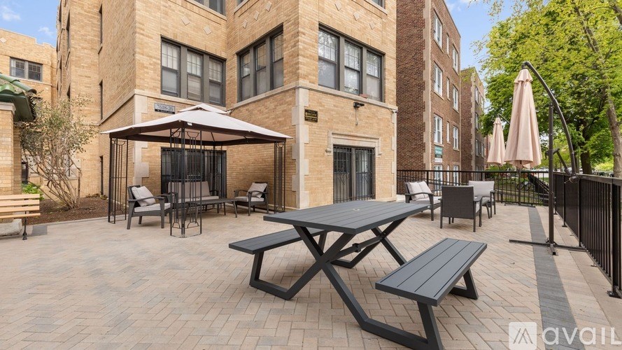A patio with a table and chairs is surrounded by a black fence.
