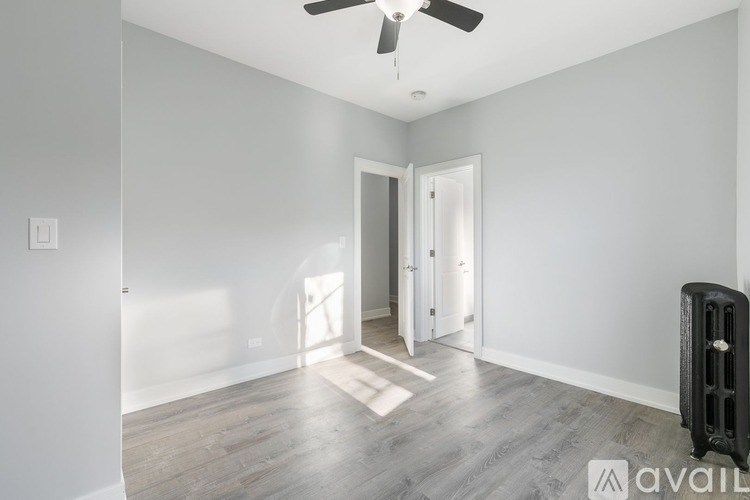 A spacious room with a ceiling fan and a doorway leading to another room.