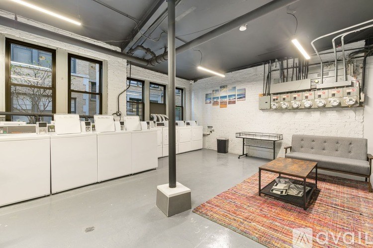 A room with a white couch, a brown coffee table, and a white wall with a shelf and a window.