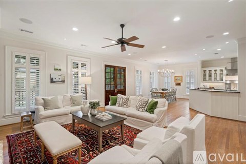 A spacious living room with a white sofa set and a rug.