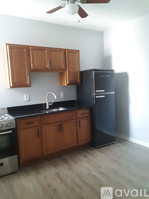 A kitchen with wooden cabinets and a black fridge.