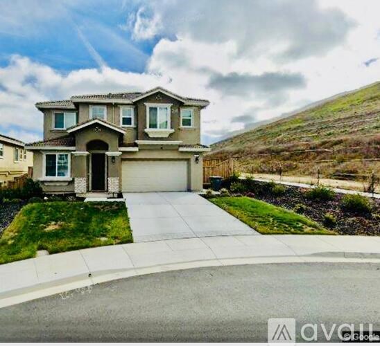 A house with a garage is situated on a hillside.