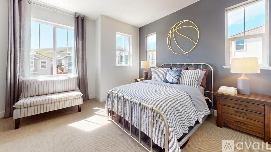 A bedroom with a large bed, a bench, and a window overlooking a residential area.