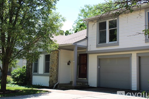 A two-story house with a garage door and a stone pillar.