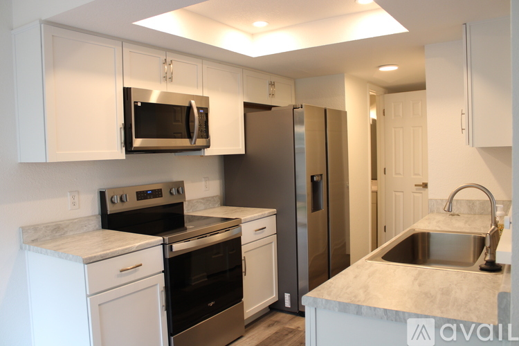 A kitchen with white cabinets and a stainless steel refrigerator.