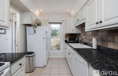 A kitchen with white cabinets and black countertops.