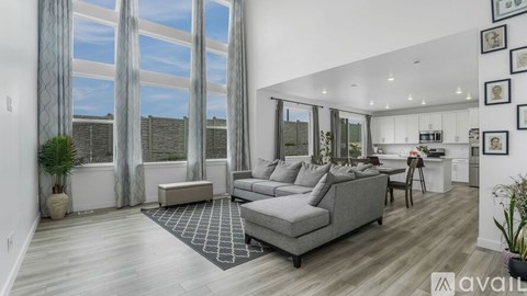 A modern living room with a grey sofa and a large window.