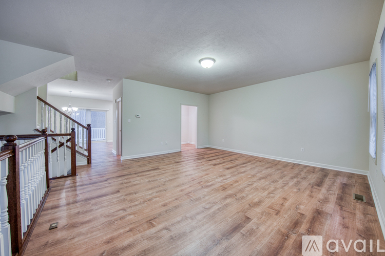 A spacious room with wooden flooring and white walls.