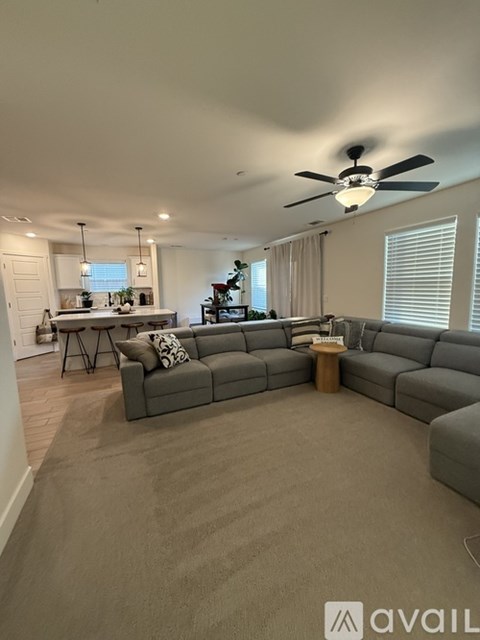 A living room with a grey sectional sofa and a ceiling fan.