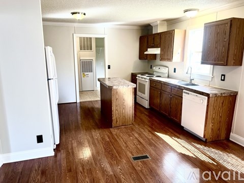 A kitchen with wooden floors and white appliances.