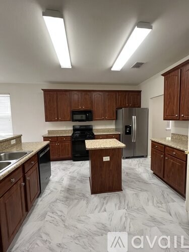 A kitchen with wooden cabinets and a marble floor.