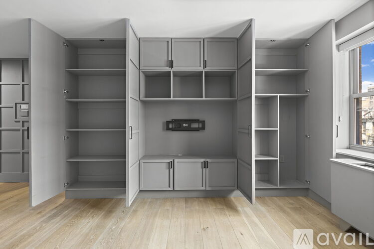 A kitchen pantry with a grey cabinet and a black fridge.