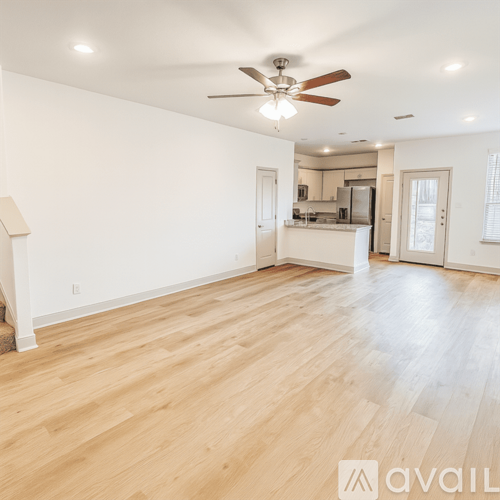 A spacious room with wooden flooring and a ceiling fan.