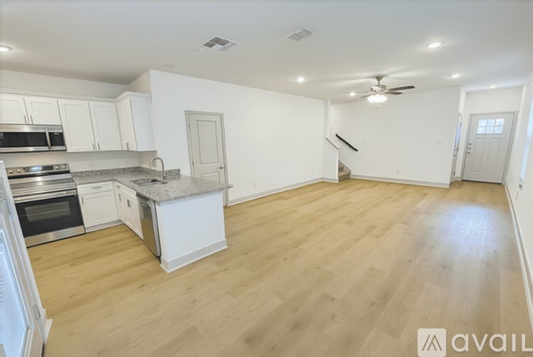 A kitchen with white cabinets and a wooden floor.
