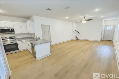 A kitchen with white cabinets and a wooden floor.