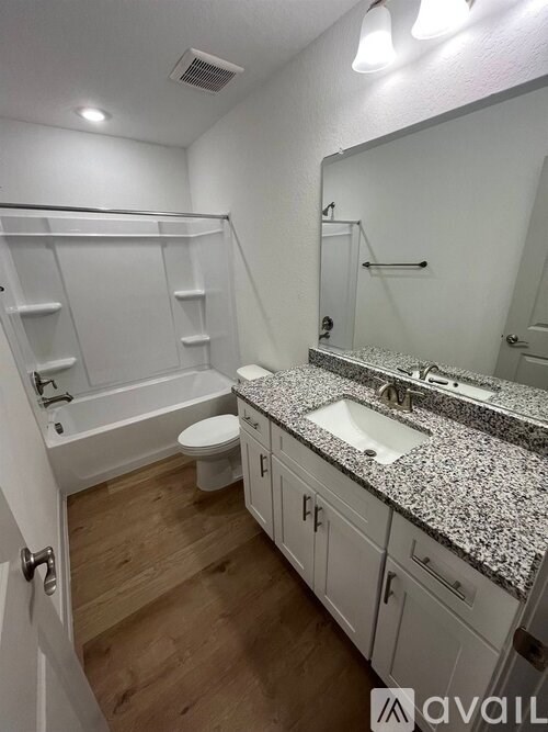 A bathroom with a granite countertop and white cabinets.