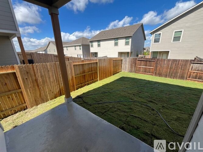 A backyard with a wooden fence and a concrete patio.