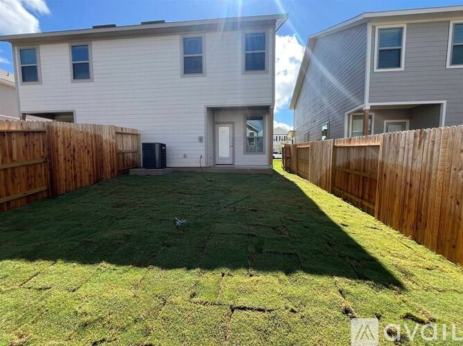 A backyard with a wooden fence and a house in the background.