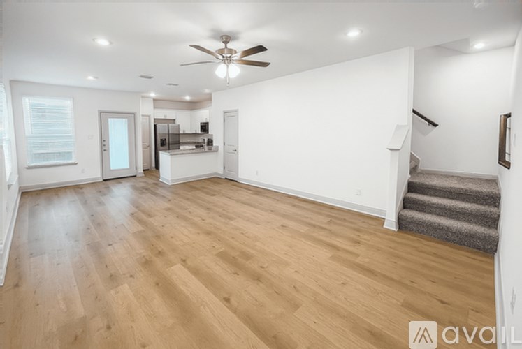 A spacious room with wooden flooring and a ceiling fan.