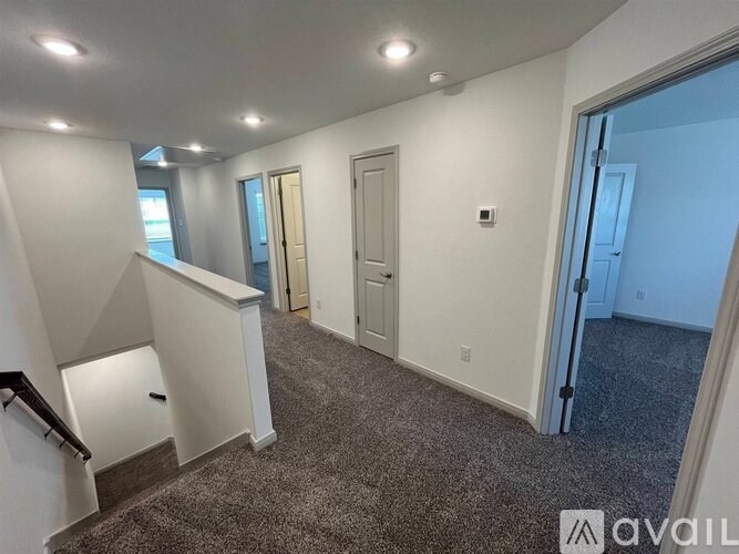 A room with a carpeted floor and a staircase on the left side.
