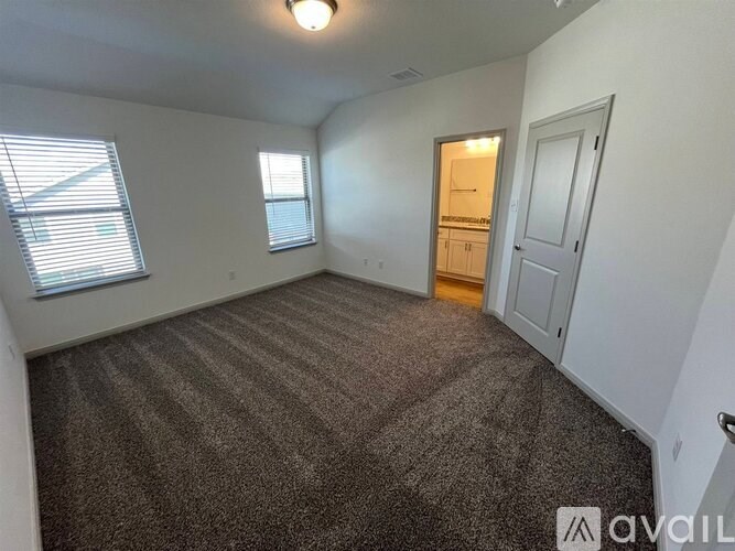 A carpeted room with a door and a window.