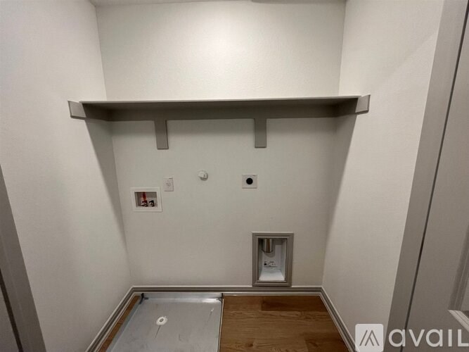 A white wall with a shelf and a small white box on the floor.