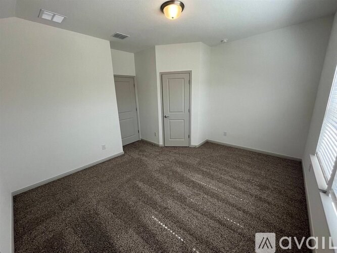 A carpeted room with a door and a window.