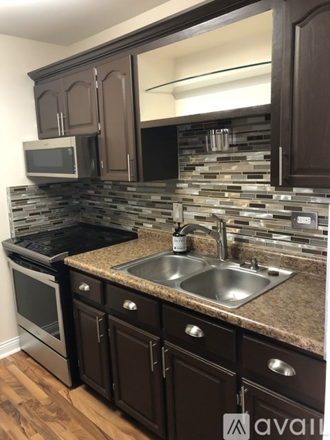 A kitchen with brown cabinets and a stone backsplash.