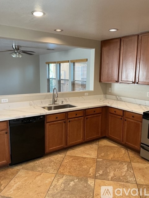 A kitchen with brown cabinets and a black dishwasher.