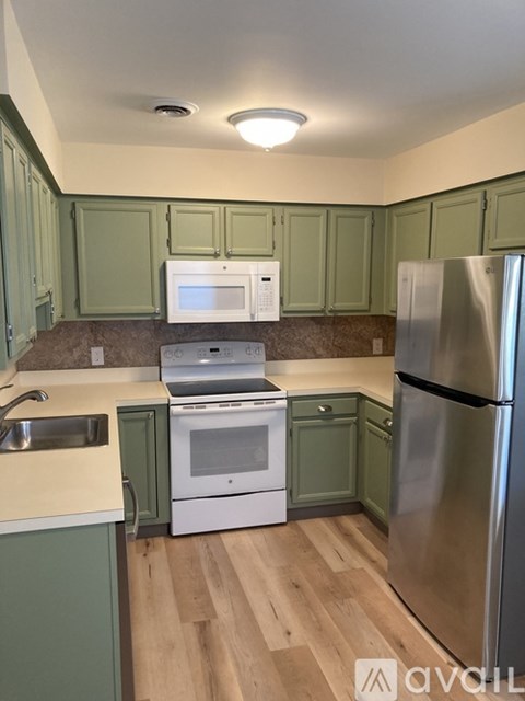 A kitchen with green cabinets and a stainless steel refrigerator.